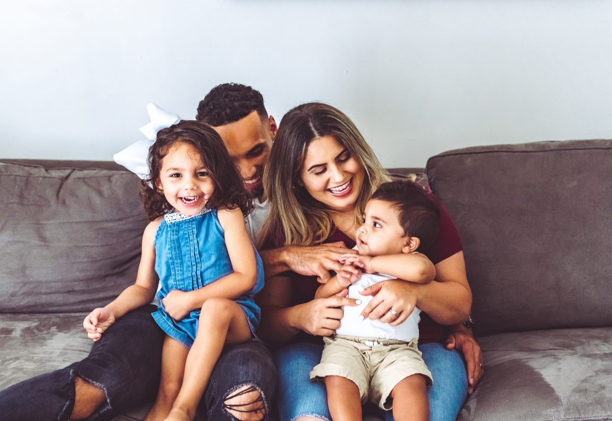 Happy multiracial family at home with two young children in casual portrait on their couch